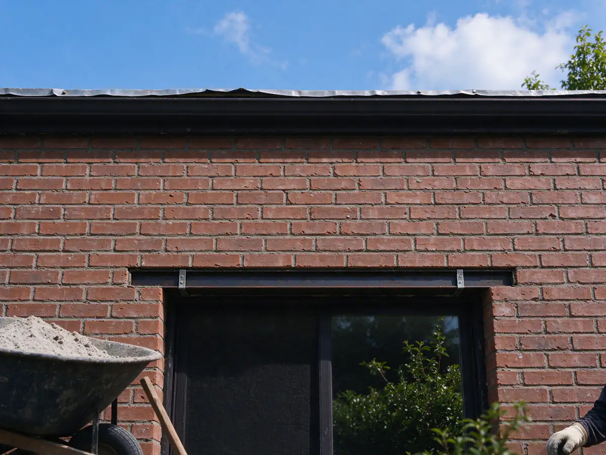 A finished brick wall above a window with matched brick and fresh joints over a new lintel